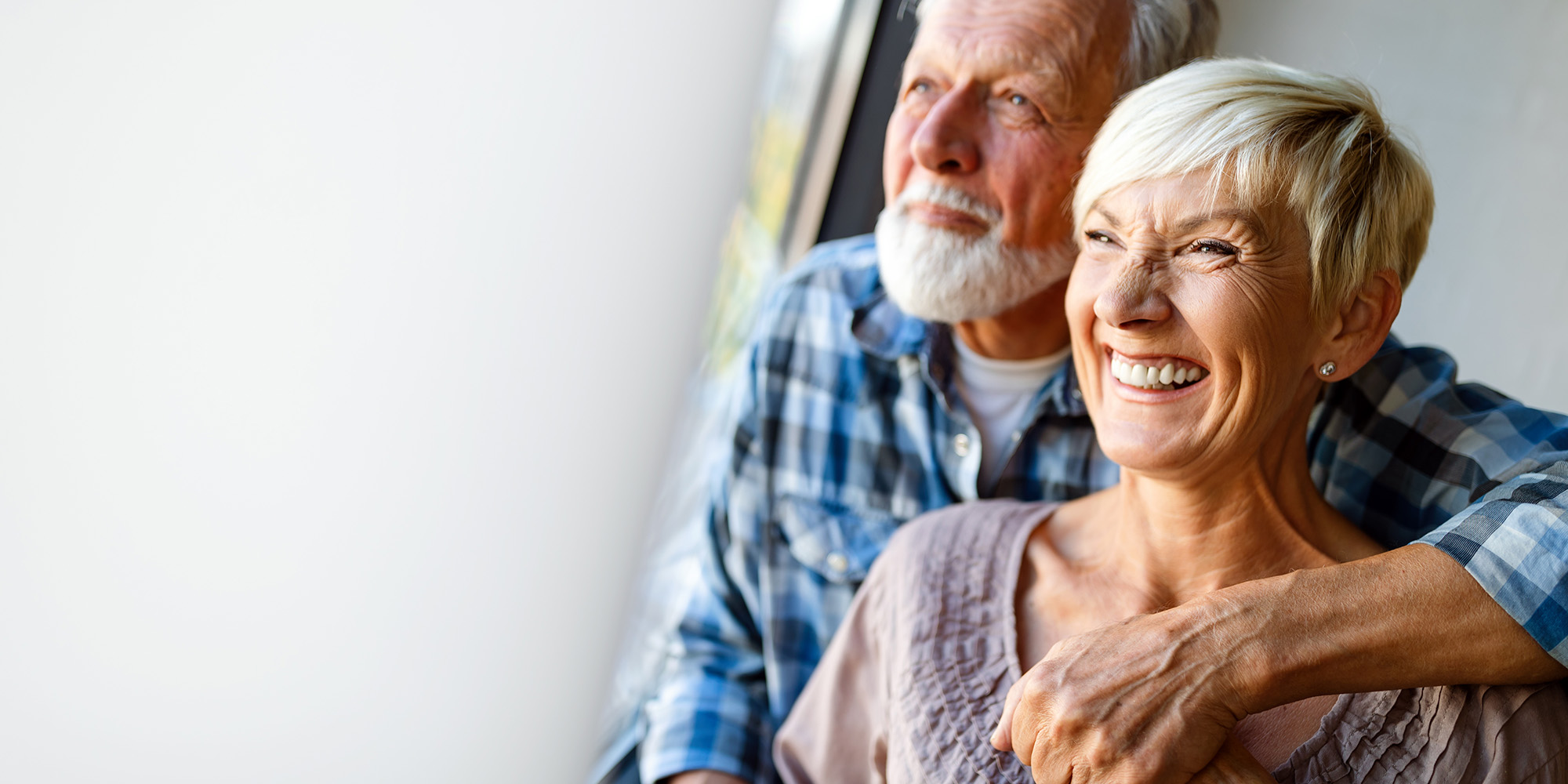 A happy elderly couple looking out the window