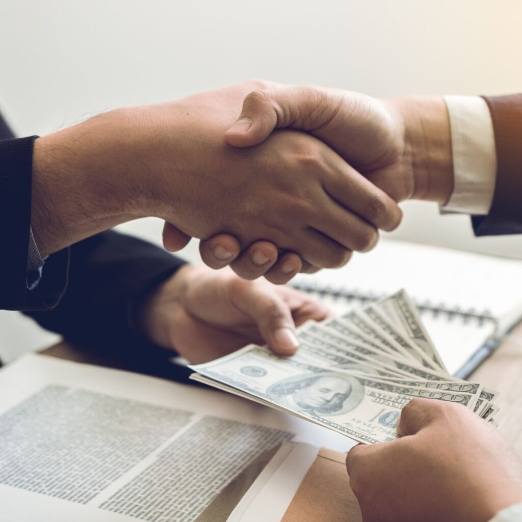Two people shaking hands and exchanging money