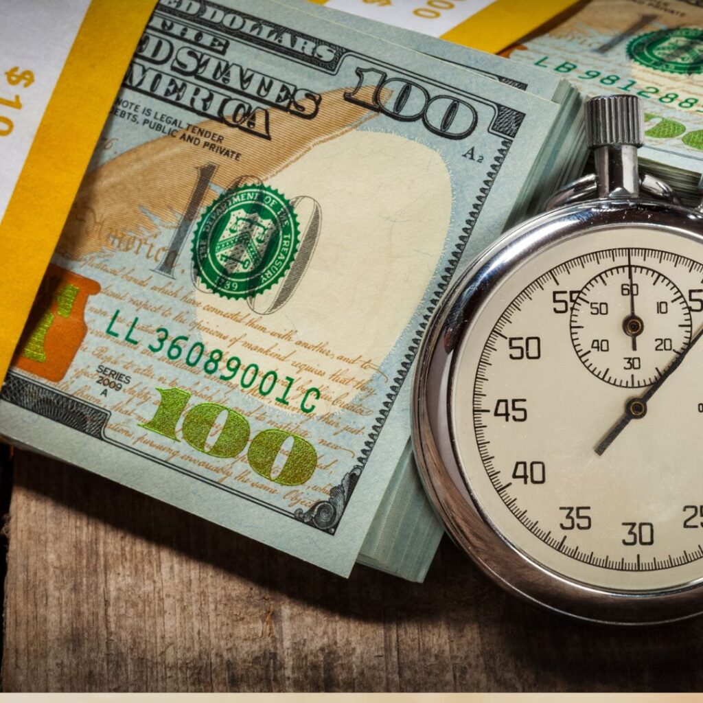 a pocket watch next to a stack of money