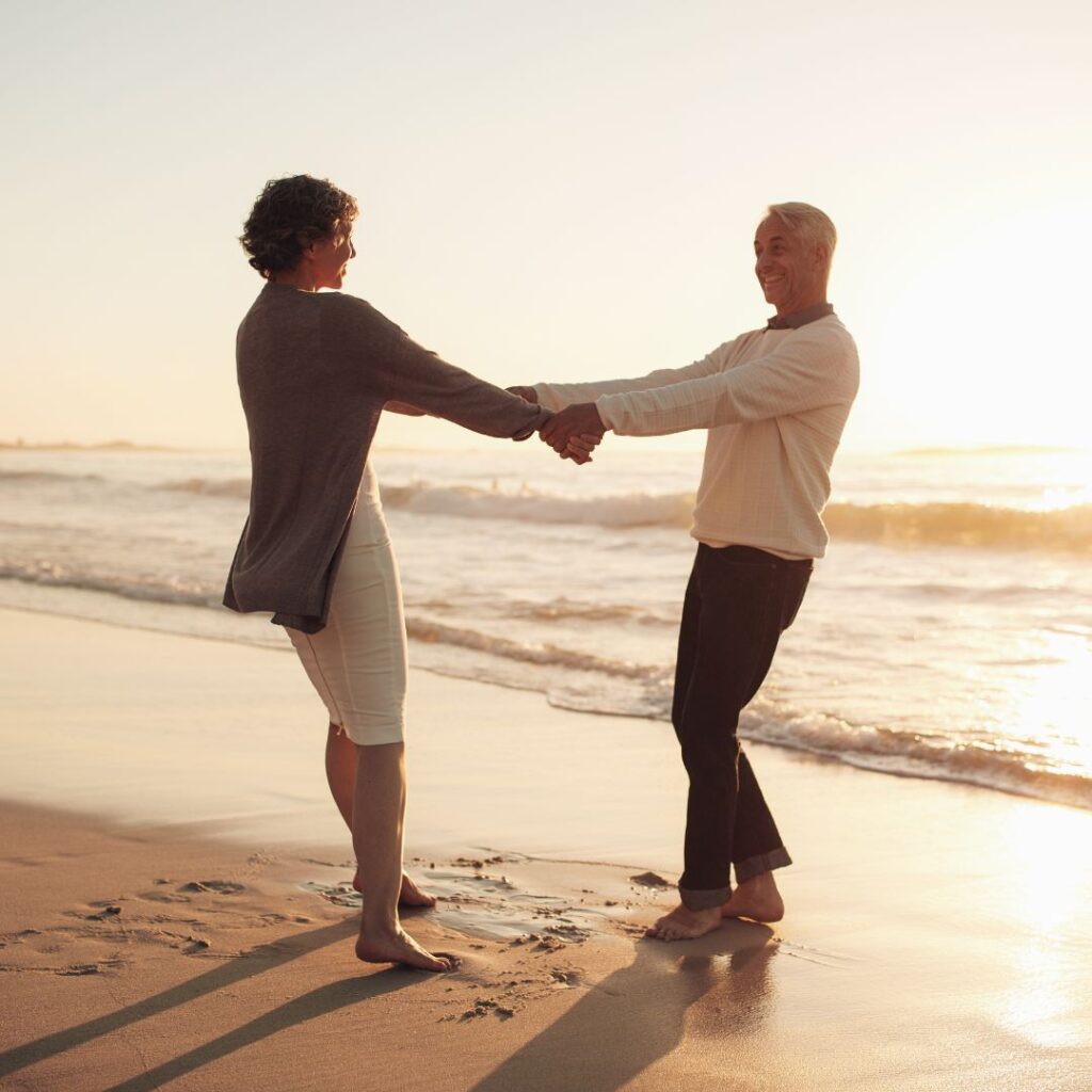 An older couple holding hands on the beach 