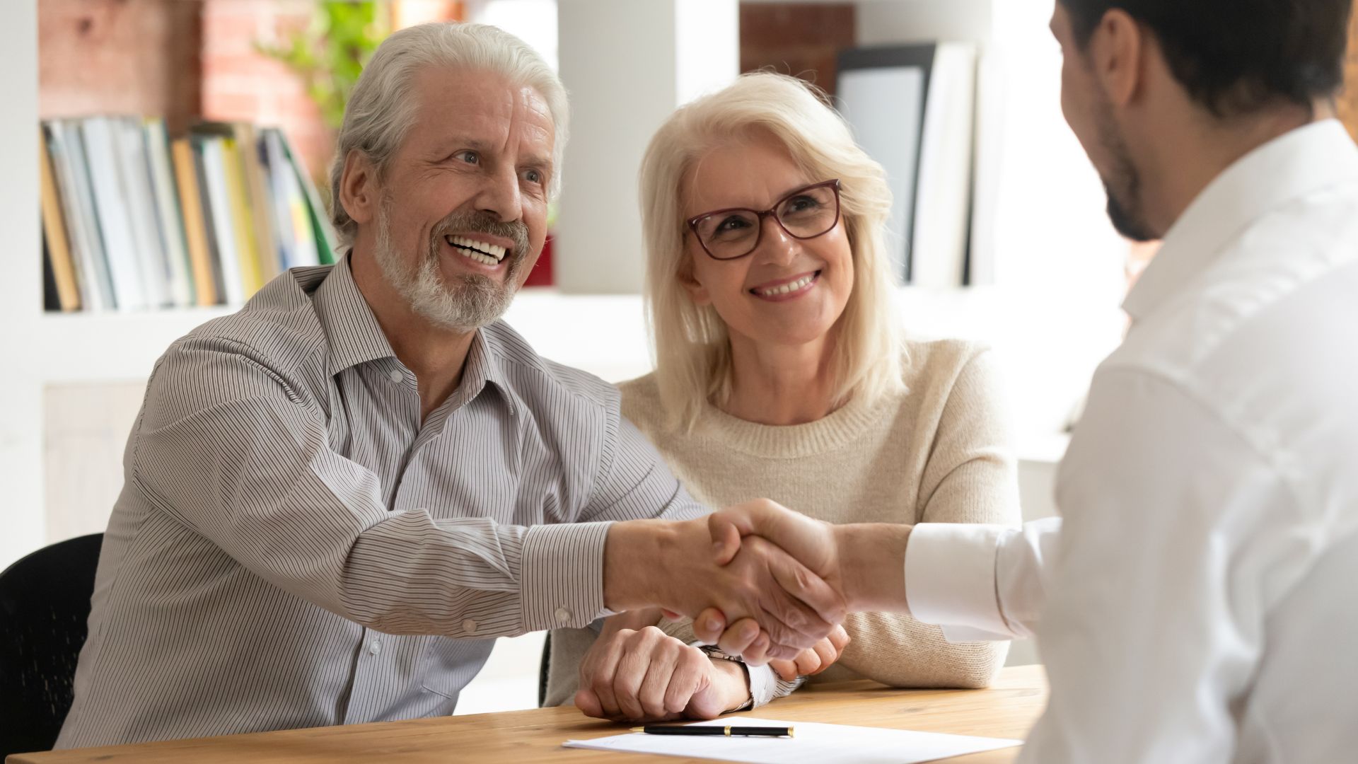 Senior couple giving a handshake to an agent