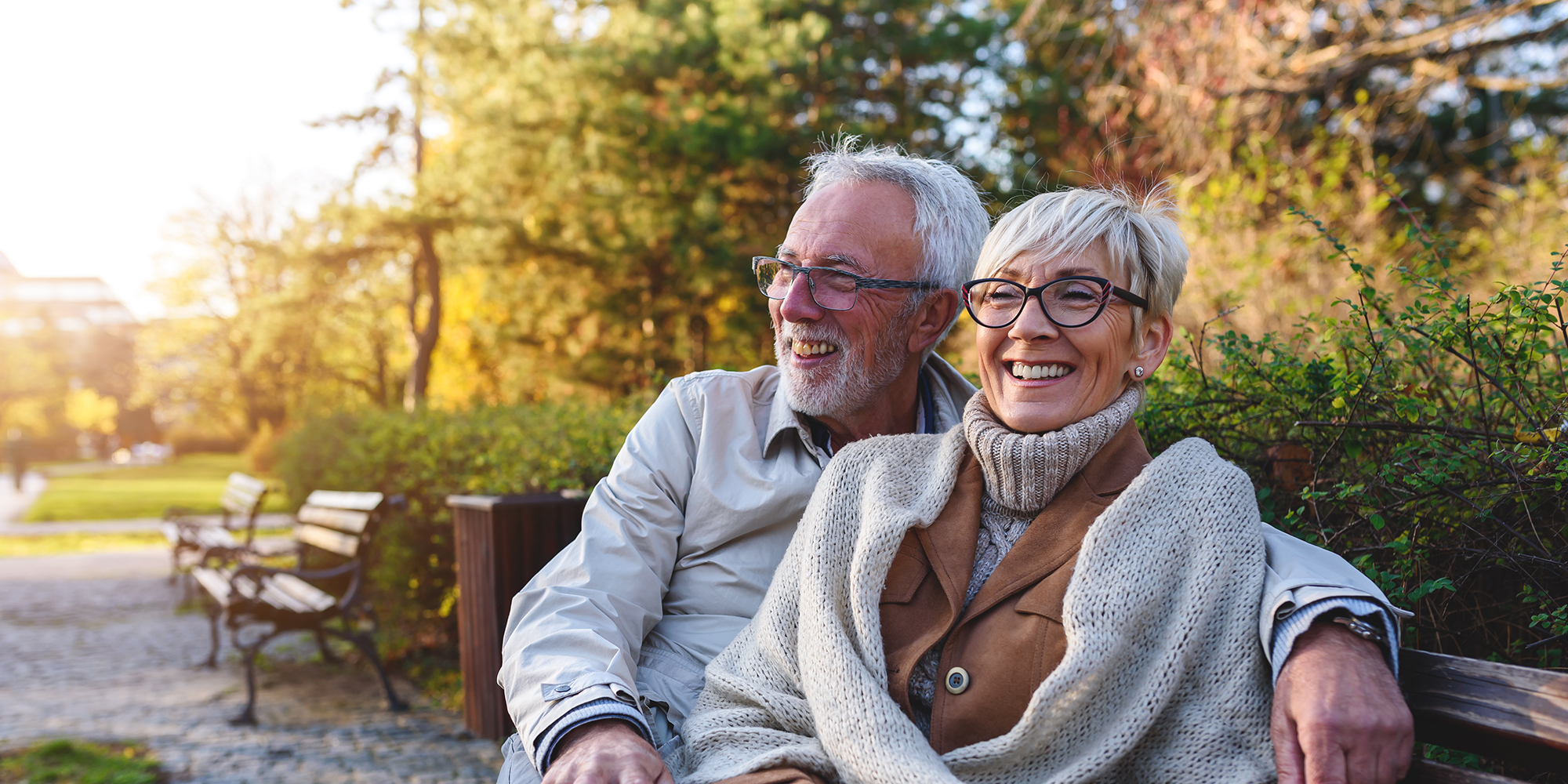 Smiling senior couple sitting on the bench in the park together