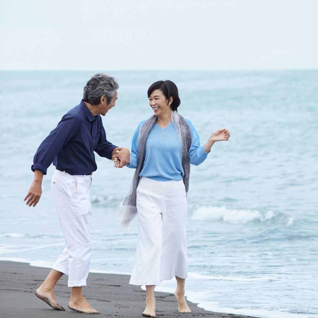 A happy mature couple walking on a beach, illustrating life after a settlement