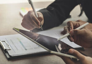 Closeup shot business consult with tablet and paperwork.